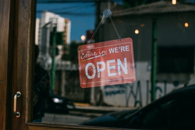 An open sign hanging in a window, inviting customers to enter the establishment.