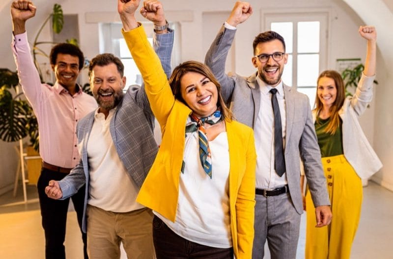 A group of business people celebrating success by raising their arms in unity.