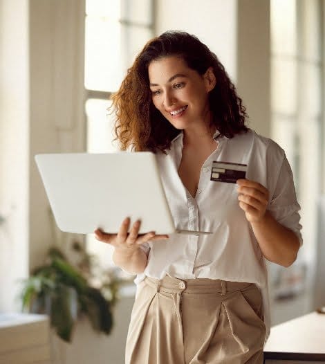 A woman using a laptop while holding a credit card for online transactions.